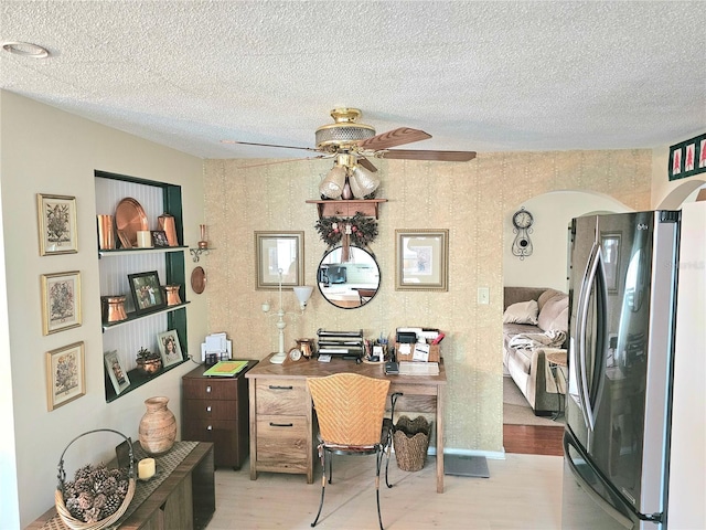 office space featuring light wood-type flooring, ceiling fan, and a textured ceiling