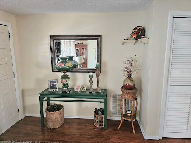 room details featuring visible vents, a textured ceiling, baseboards, and wood finished floors