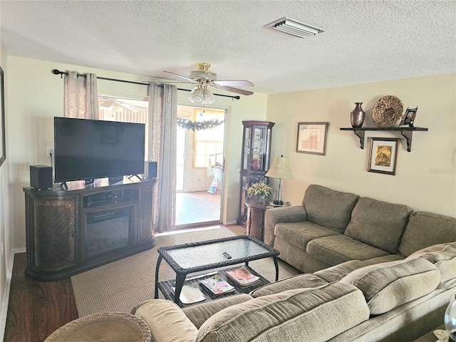 living area with a textured ceiling, visible vents, and a ceiling fan