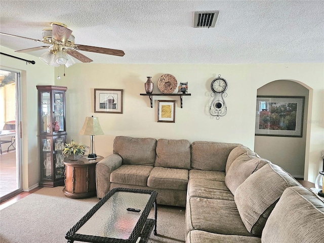 living area featuring a textured ceiling, ceiling fan, carpet floors, and visible vents