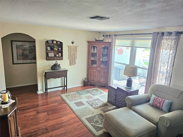 living room featuring a textured ceiling, wood finished floors, visible vents, and baseboards