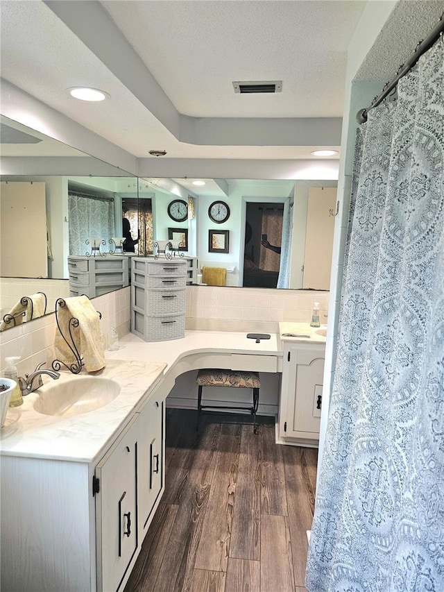 full bath featuring tasteful backsplash, visible vents, a textured ceiling, vanity, and wood finished floors