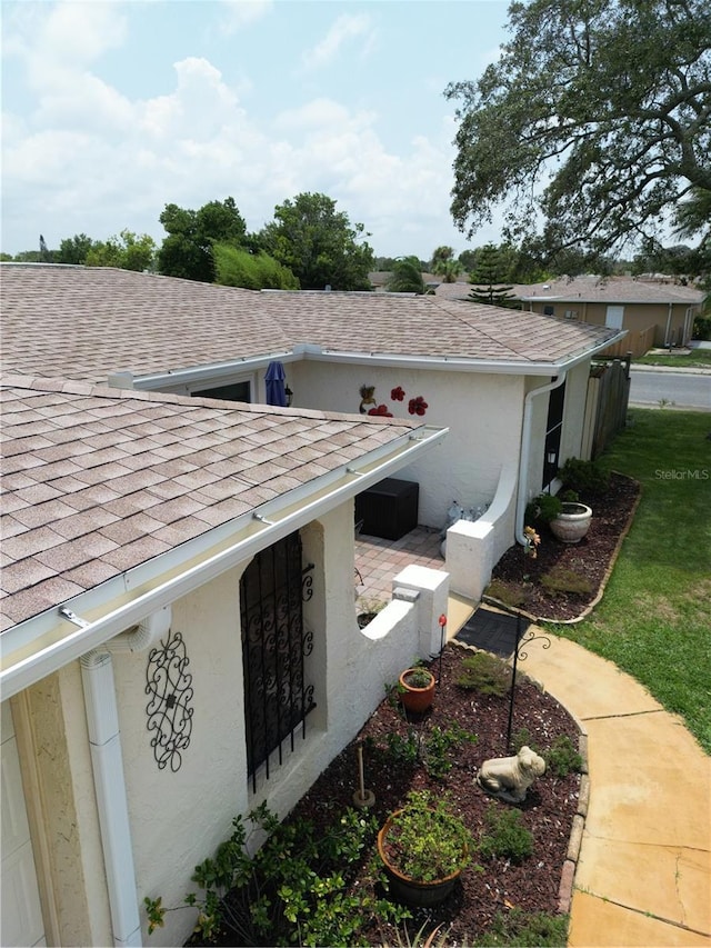 view of property exterior with a shingled roof and stucco siding