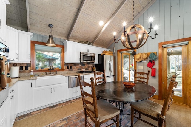 dining room with a notable chandelier, sink, and vaulted ceiling