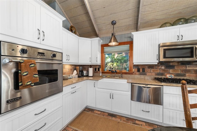 kitchen with appliances with stainless steel finishes, sink, white cabinets, and hanging light fixtures