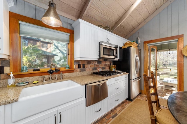 kitchen with appliances with stainless steel finishes, plenty of natural light, wood ceiling, and light stone countertops