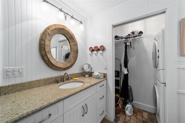 bathroom with ornamental molding, stacked washer / drying machine, and vanity