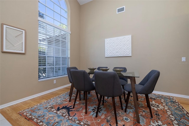 dining area with hardwood / wood-style flooring and a towering ceiling