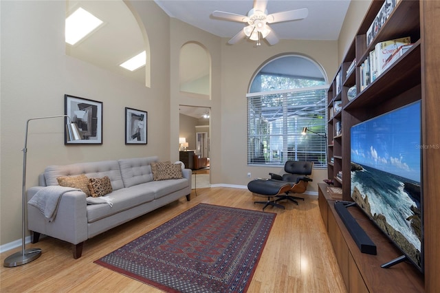 living room with ceiling fan, high vaulted ceiling, and light hardwood / wood-style flooring