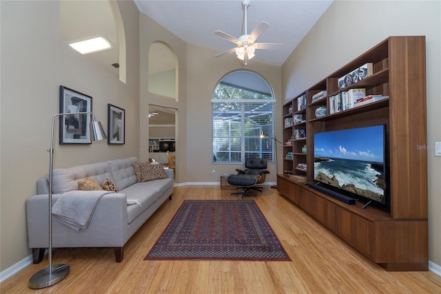 living room with ceiling fan, high vaulted ceiling, and light hardwood / wood-style floors