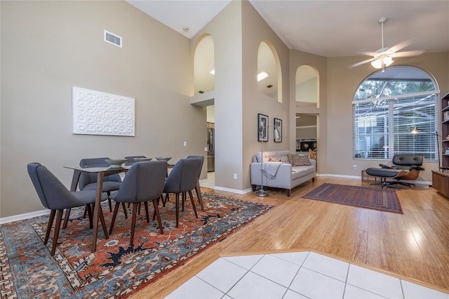 tiled dining space with a towering ceiling and ceiling fan