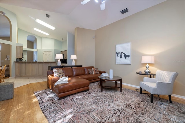 living room featuring high vaulted ceiling, ceiling fan, and light wood-type flooring