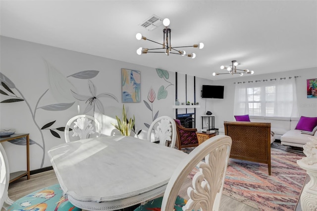 dining room with a fireplace, an inviting chandelier, and light wood-type flooring