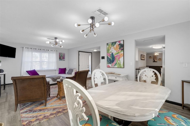 dining space with light hardwood / wood-style flooring and a notable chandelier