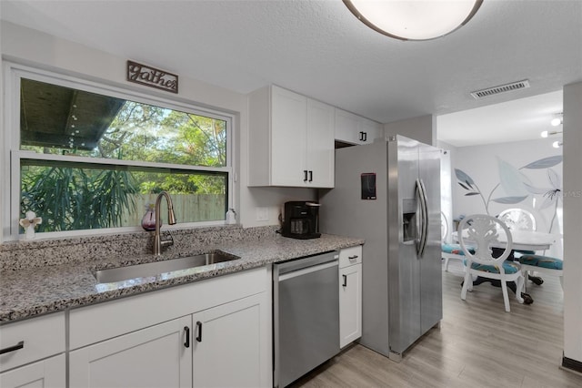 kitchen featuring sink, light wood-type flooring, light stone counters, white cabinetry, and stainless steel appliances