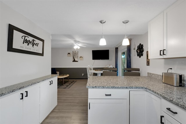 kitchen with kitchen peninsula, ceiling fan, pendant lighting, white cabinets, and light hardwood / wood-style floors