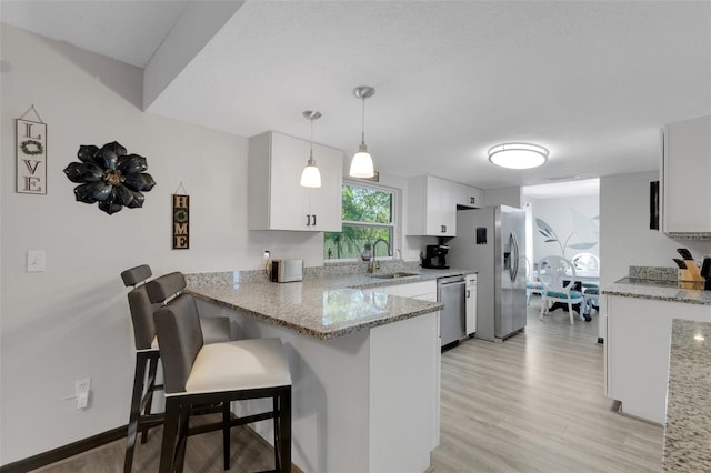 kitchen with pendant lighting, a breakfast bar, white cabinets, appliances with stainless steel finishes, and kitchen peninsula