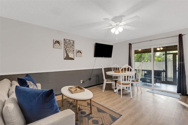 living room featuring a textured ceiling, light hardwood / wood-style floors, and ceiling fan