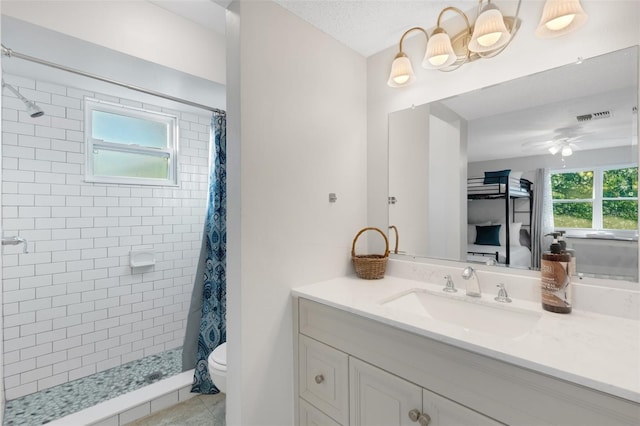 bathroom with ceiling fan, vanity, a healthy amount of sunlight, and toilet