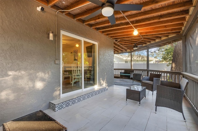 sunroom / solarium featuring beam ceiling and ceiling fan