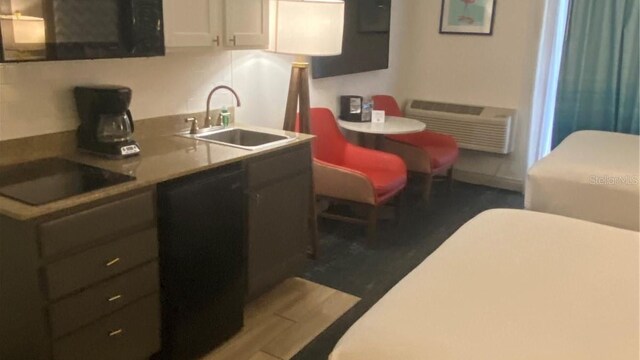 kitchen featuring a wall unit AC, white cabinetry, black appliances, dark hardwood / wood-style flooring, and sink