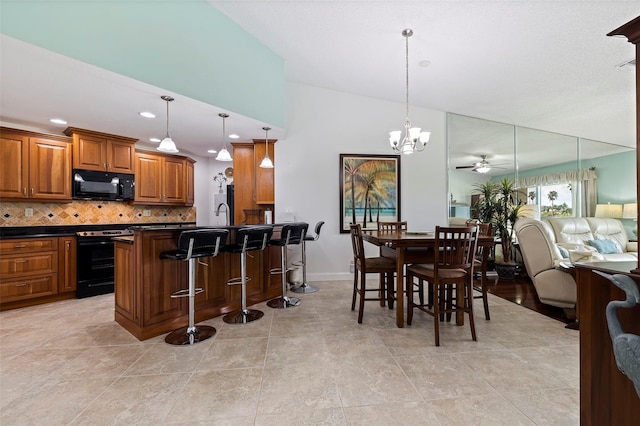 kitchen featuring ceiling fan with notable chandelier, range with electric stovetop, decorative backsplash, a kitchen bar, and decorative light fixtures