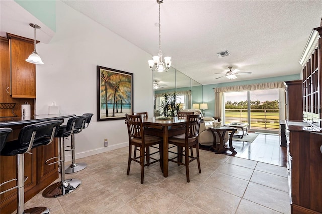 tiled dining room with ceiling fan with notable chandelier, a textured ceiling, and lofted ceiling