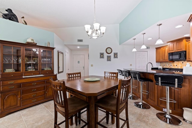 dining room with light tile patterned floors, vaulted ceiling, sink, and an inviting chandelier