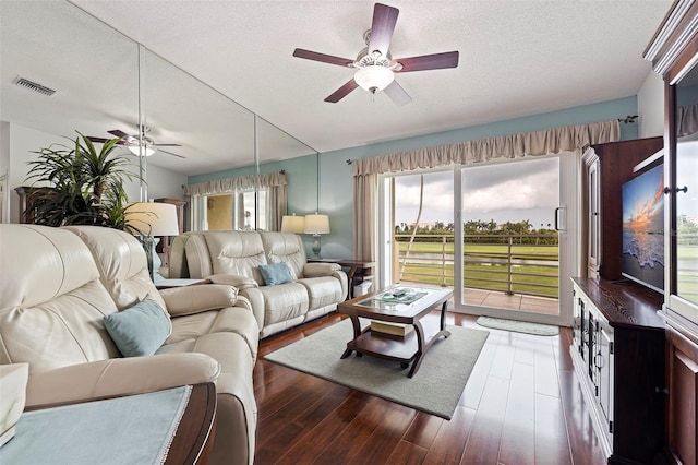 living room featuring ceiling fan, dark wood-type flooring, and a textured ceiling