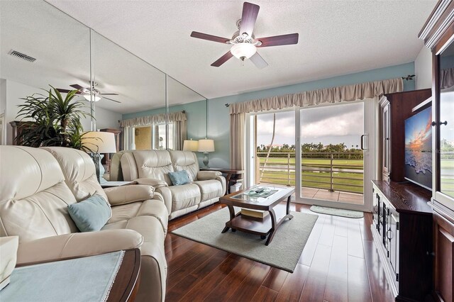 living room featuring dark wood finished floors, a ceiling fan, and a healthy amount of sunlight