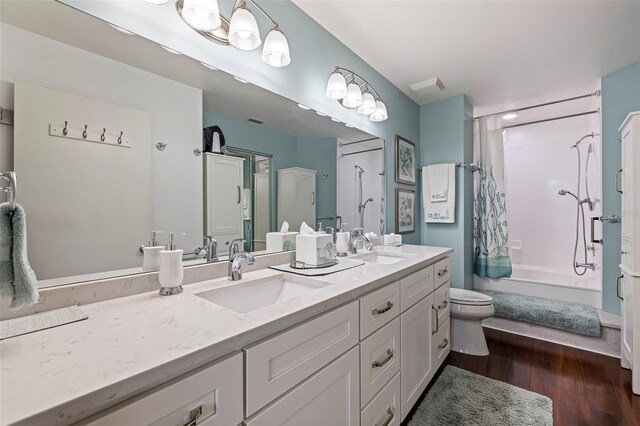 full bath with shower / tub combo with curtain, wood finished floors, a sink, and double vanity