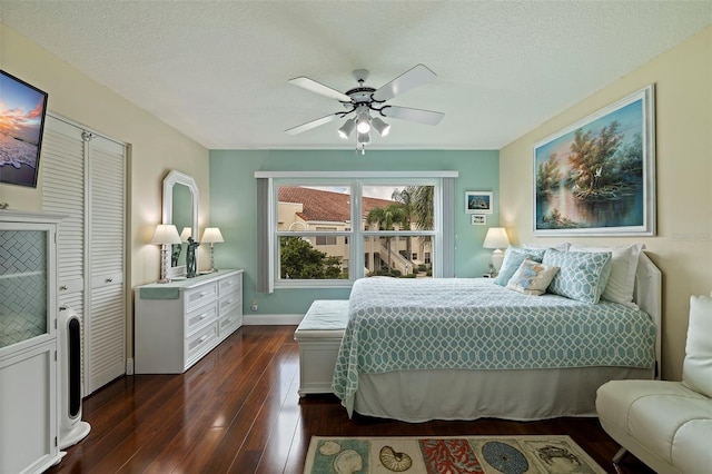 bedroom featuring a closet, a textured ceiling, dark wood-type flooring, and ceiling fan