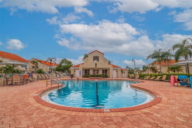 community pool featuring a patio area, fence, and a residential view