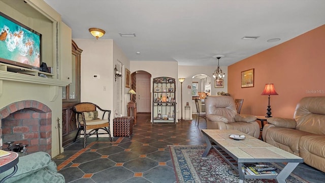 living room with visible vents, a fireplace, arched walkways, and a notable chandelier