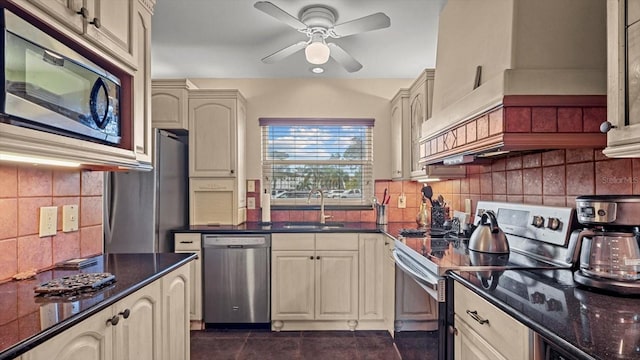 kitchen featuring ceiling fan, sink, cream cabinets, dark tile patterned flooring, and appliances with stainless steel finishes