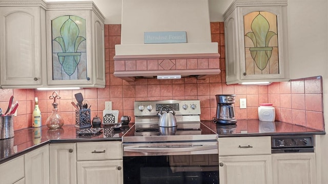 kitchen with dark countertops, tasteful backsplash, electric stove, and cream cabinets