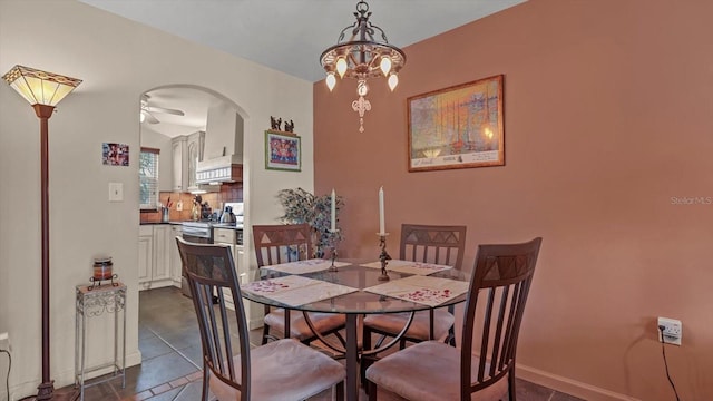 tiled dining space with ceiling fan with notable chandelier