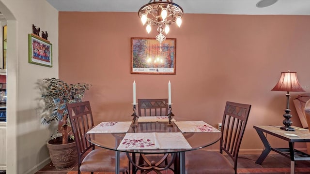 dining space featuring arched walkways, baseboards, and an inviting chandelier