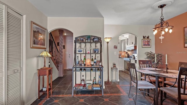 dining area with stairs, arched walkways, and a chandelier