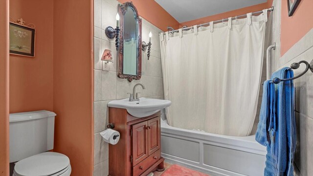 full bathroom with shower / bath combo, vanity, toilet, and tile walls