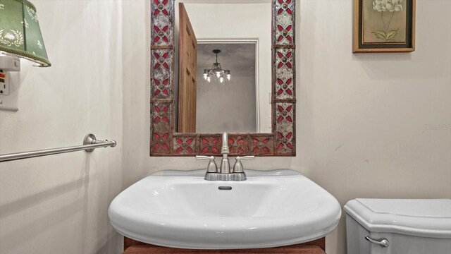 bathroom featuring sink, an inviting chandelier, and toilet