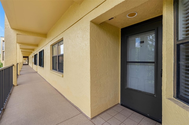 entrance to property featuring a balcony and stucco siding