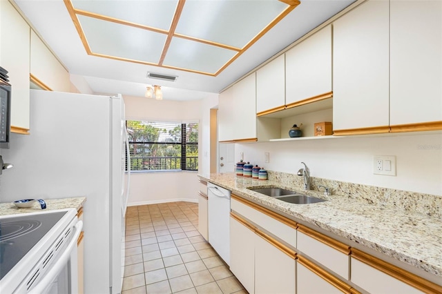 kitchen with white appliances, white cabinetry, a sink, and light tile patterned flooring