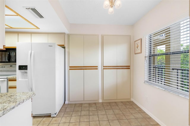 kitchen featuring light stone counters, visible vents, light tile patterned flooring, white appliances, and baseboards