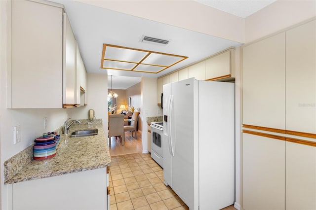 kitchen with visible vents, white cabinets, a sink, light stone countertops, and white appliances