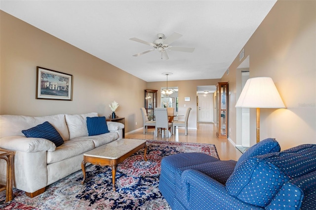 living area with a ceiling fan, light wood-style flooring, and baseboards