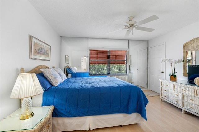 bedroom with light wood-type flooring, multiple windows, and a textured ceiling