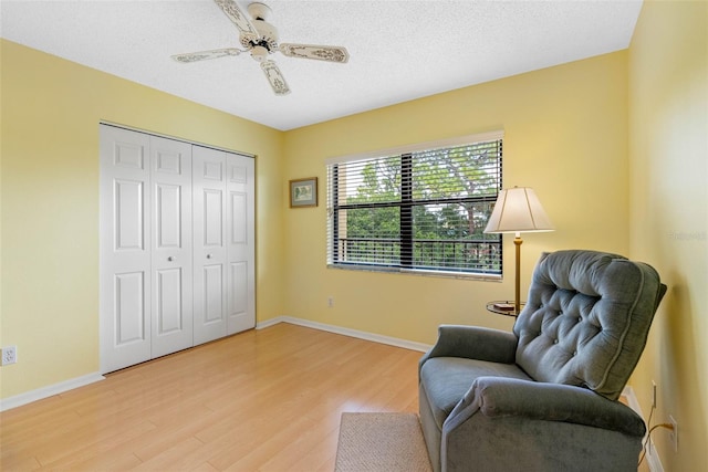 living area with light wood finished floors, baseboards, and a textured ceiling