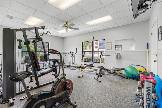 gym featuring wainscoting, a drop ceiling, ceiling fan, and visible vents