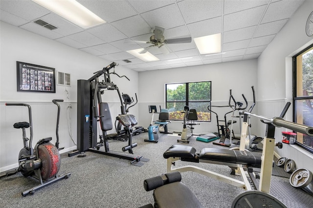 gym with a paneled ceiling, visible vents, and wainscoting